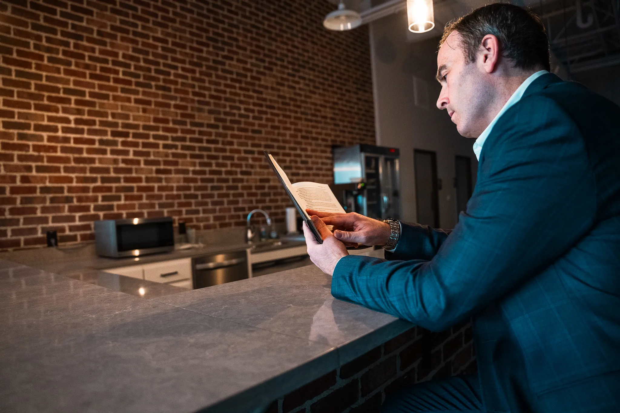 Andrew Barnhill reading a printed book at a kitchen counter